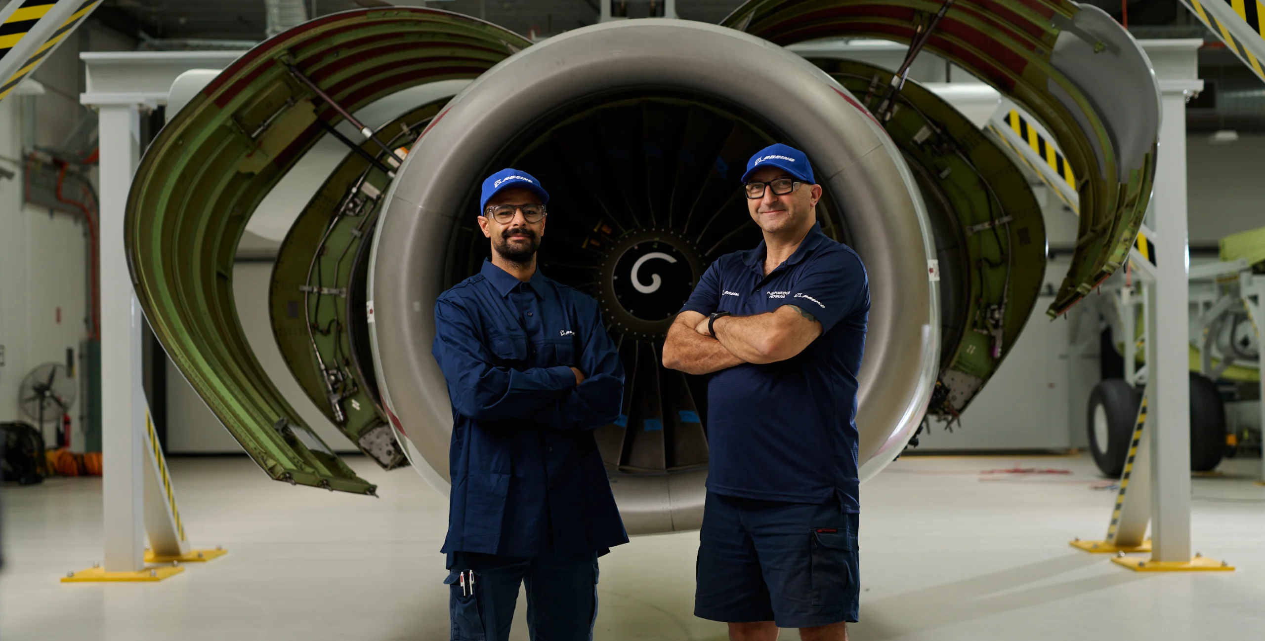Boeing Aerospace Technicians in front of a jet engine nacelle with side covers open for maintenance.