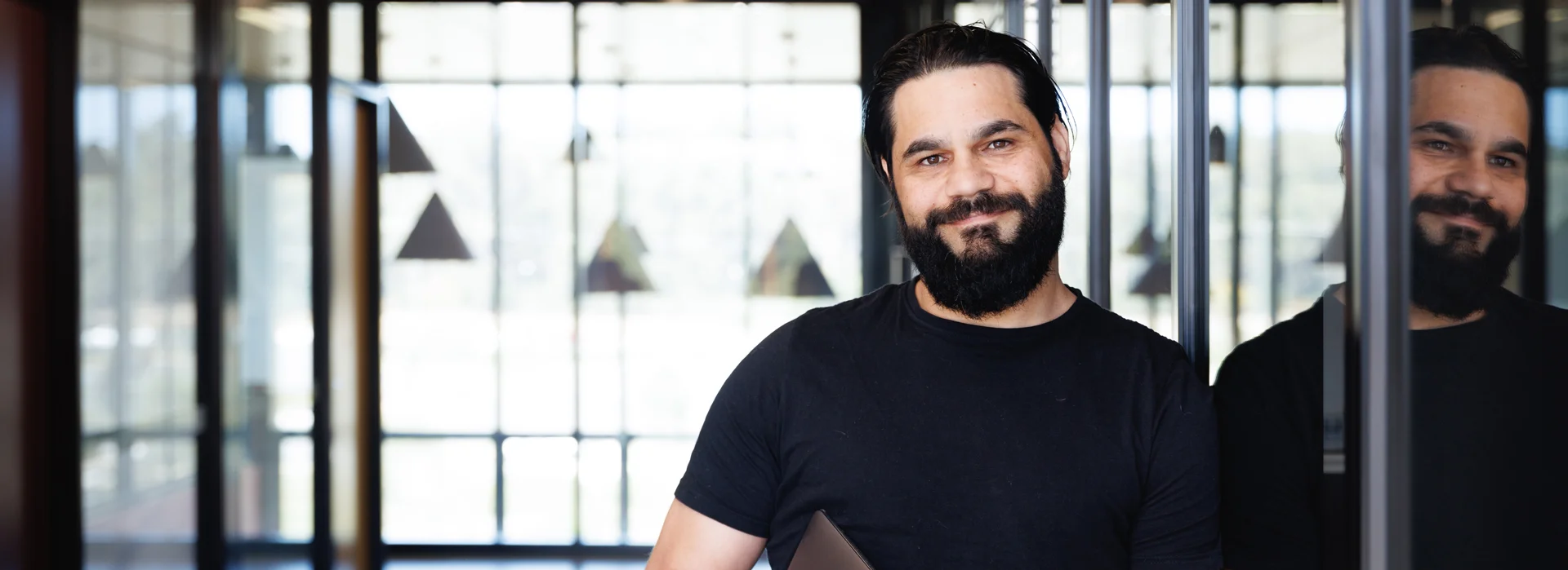 Indigenous Australian man leaning against wall smiling