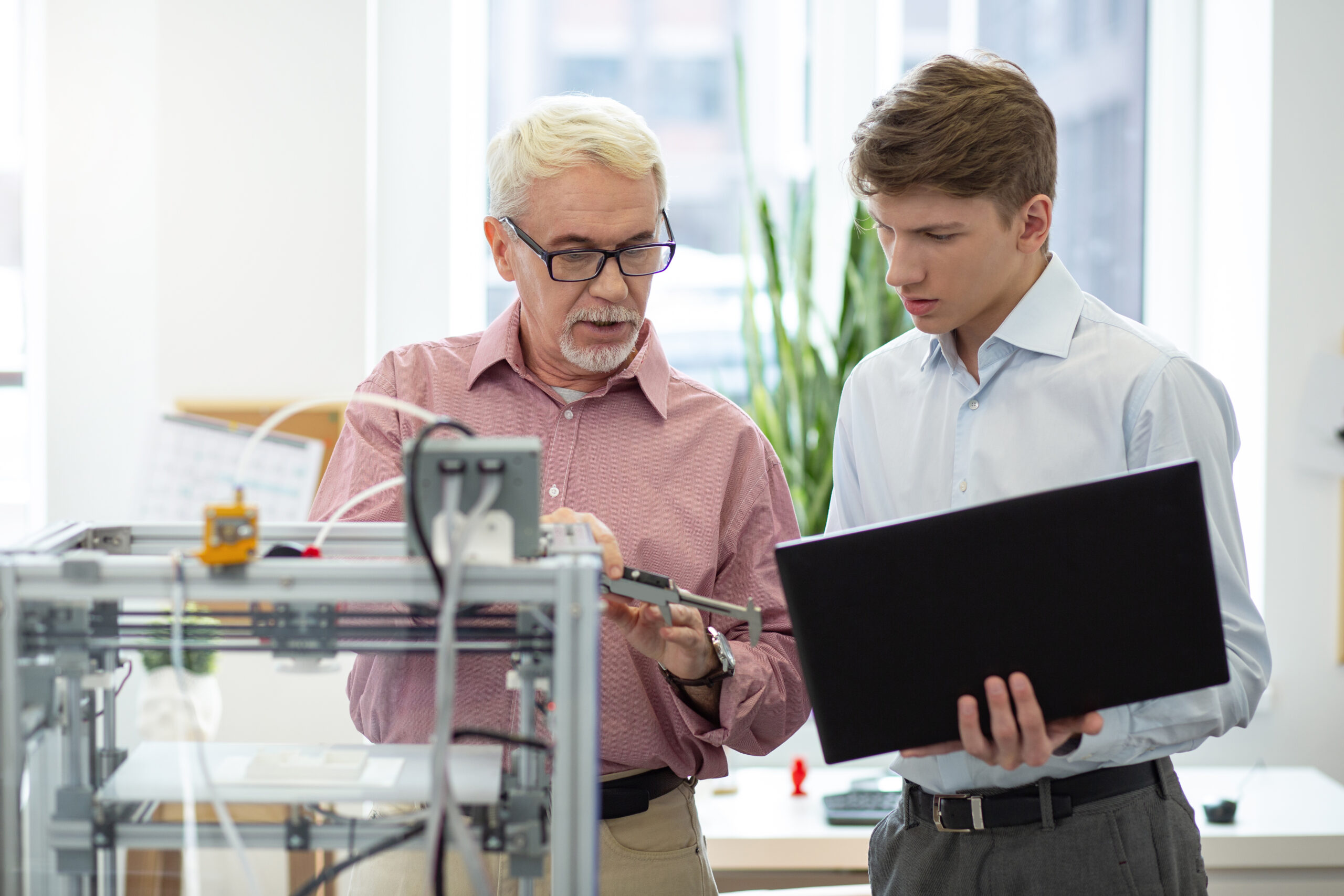 Pleasant senior engineer telling measurements to his intern