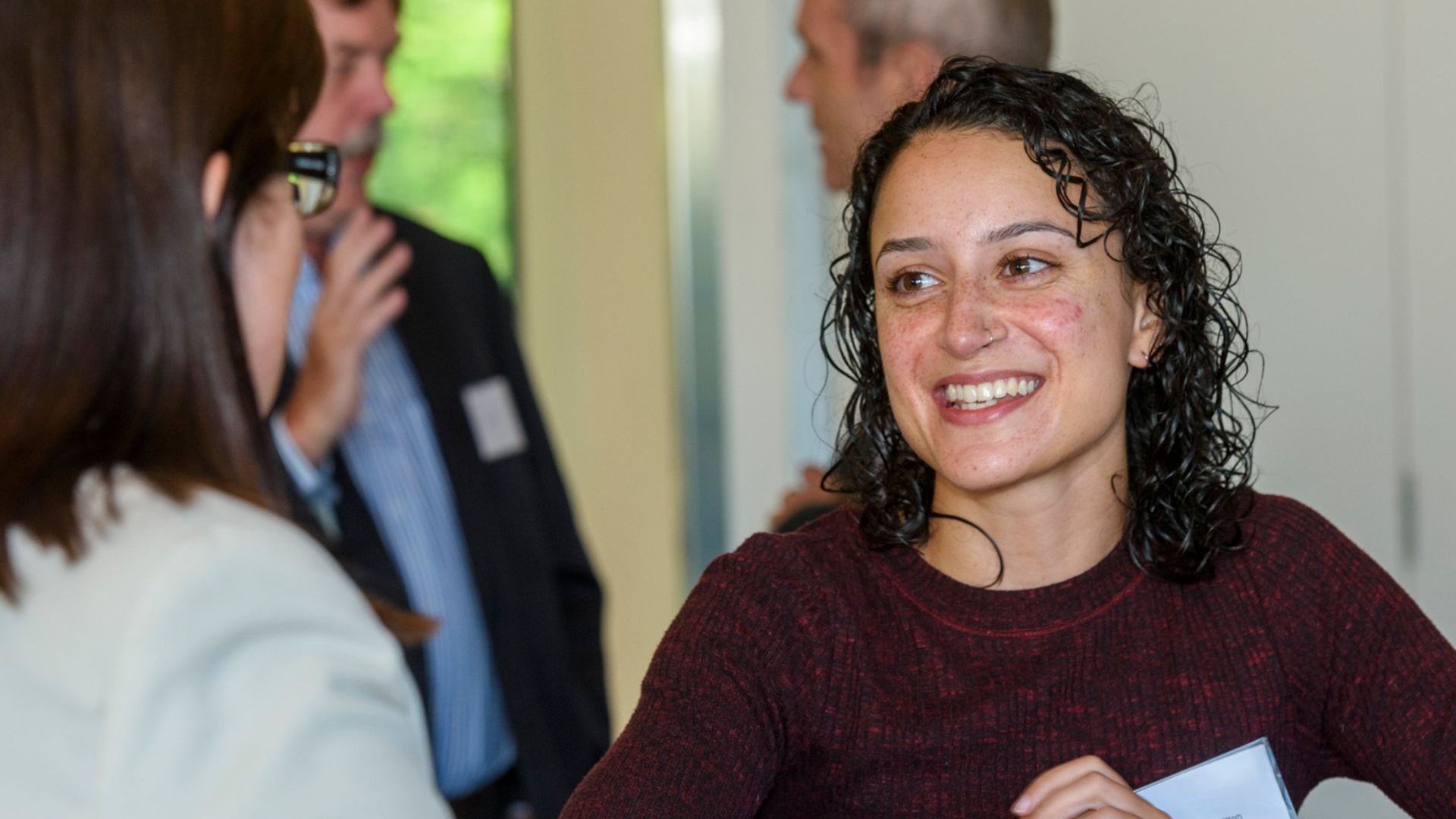 A woman smiles at her colleague off camera during a networking event