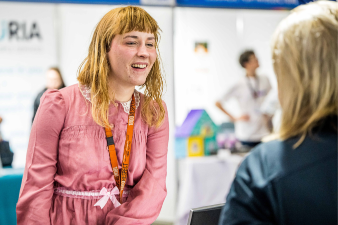 A young woman speaks with someone off camera at an event